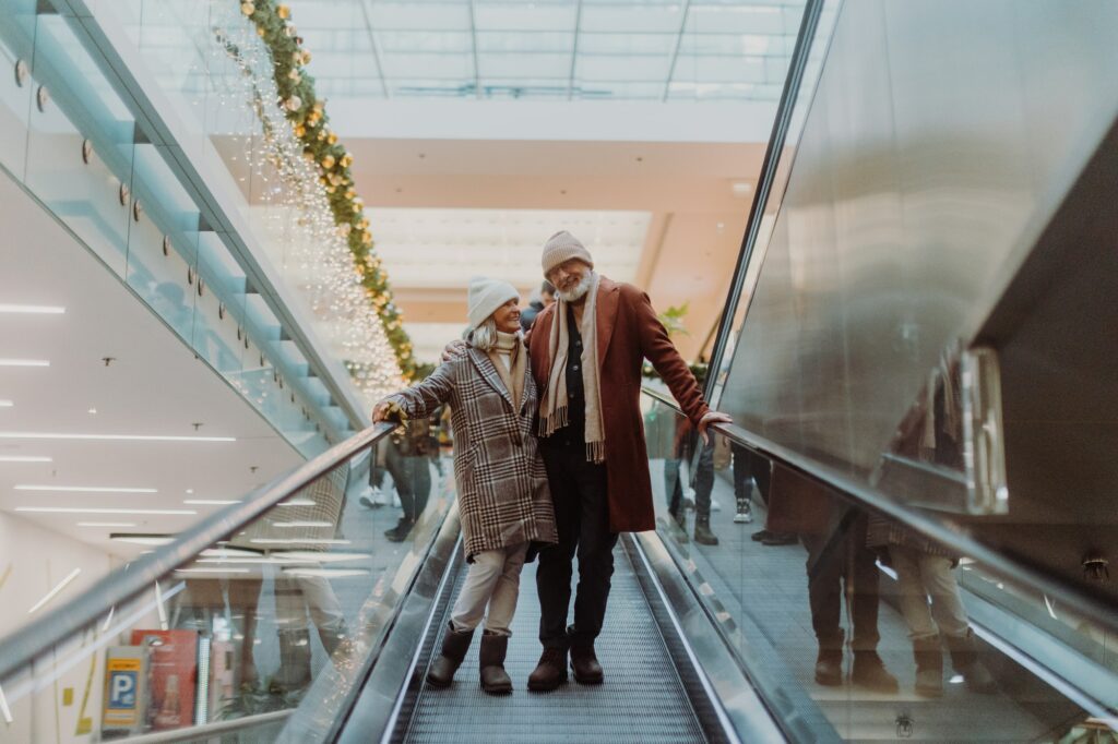 Senior couple on an escalator in a shopping mall, Christmas shopping in the city.